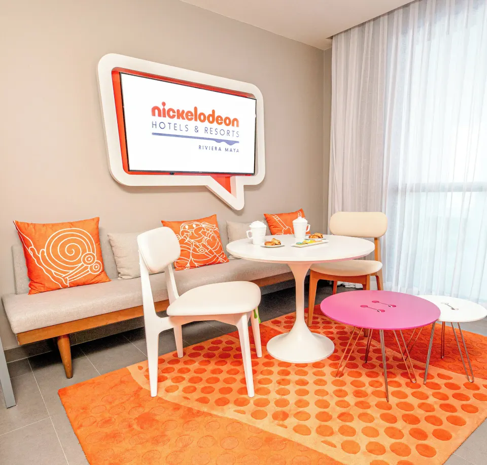 Oceanfront Swim-Up Suite seating nook with wall TV at Nickelodeon Hotels & Resorts Riviera Maya.