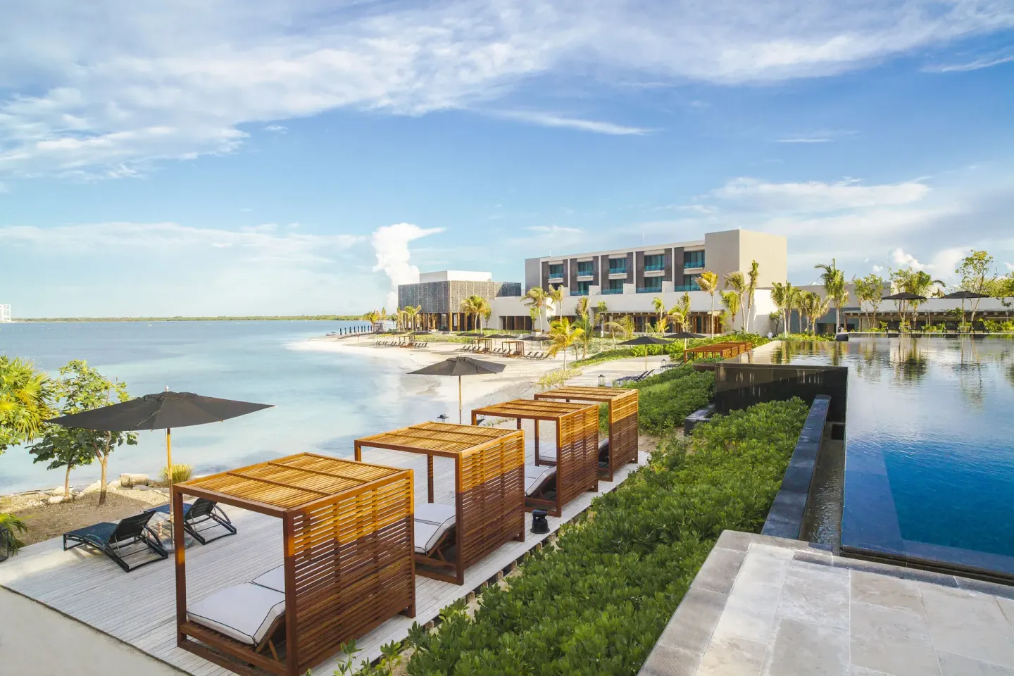 Beach cabanas, a pool, and resort buildings line the shoreline at Nizuc Resort and Spa.