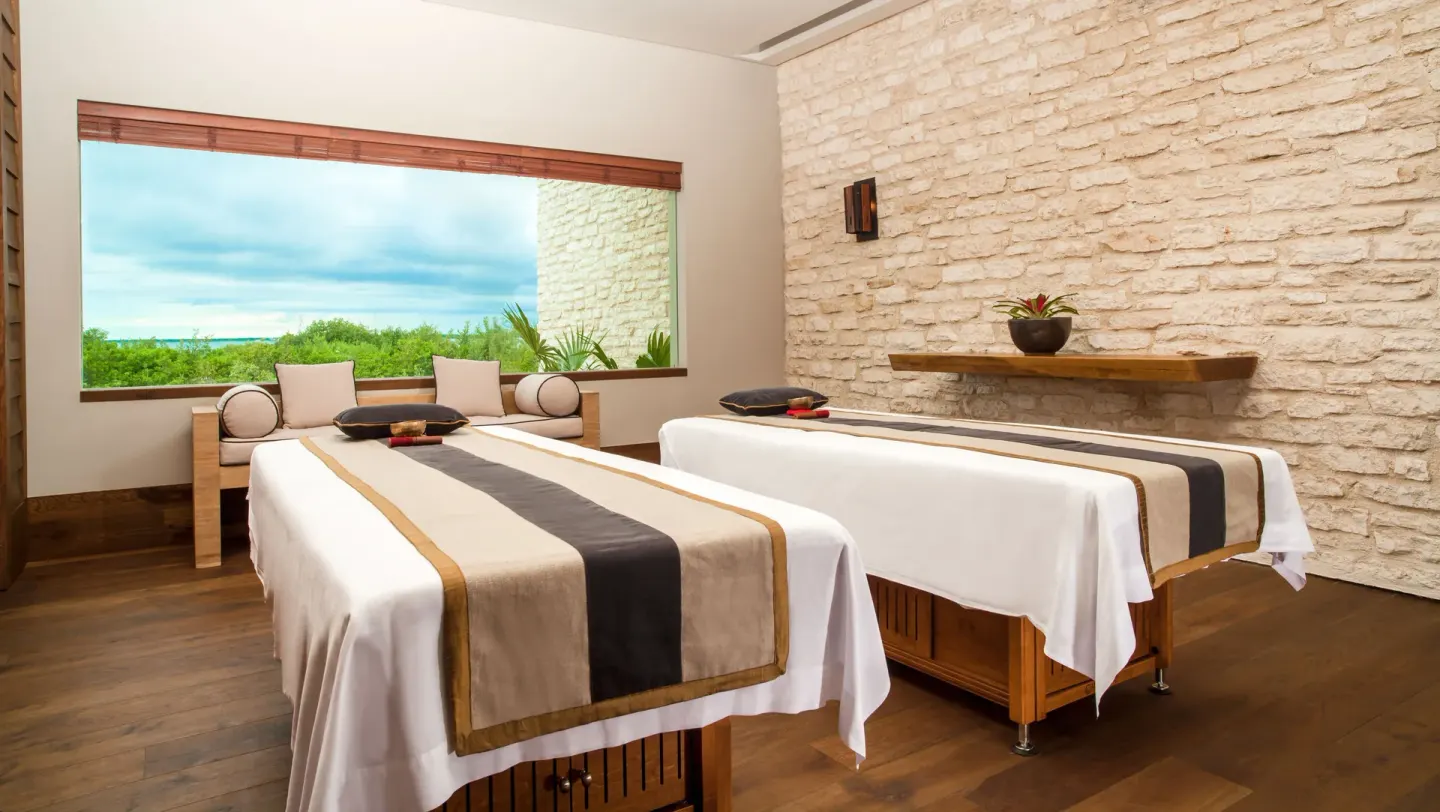 Spa treatment room with two massage tables and a garden view at Nizuc Resort and Spa.
