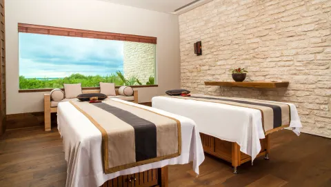 Spa treatment room with two massage tables and a garden view at Nizuc Resort and Spa.