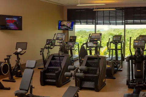 Fitness room with cardio machines and large windows at Nizuc Resort and Spa.