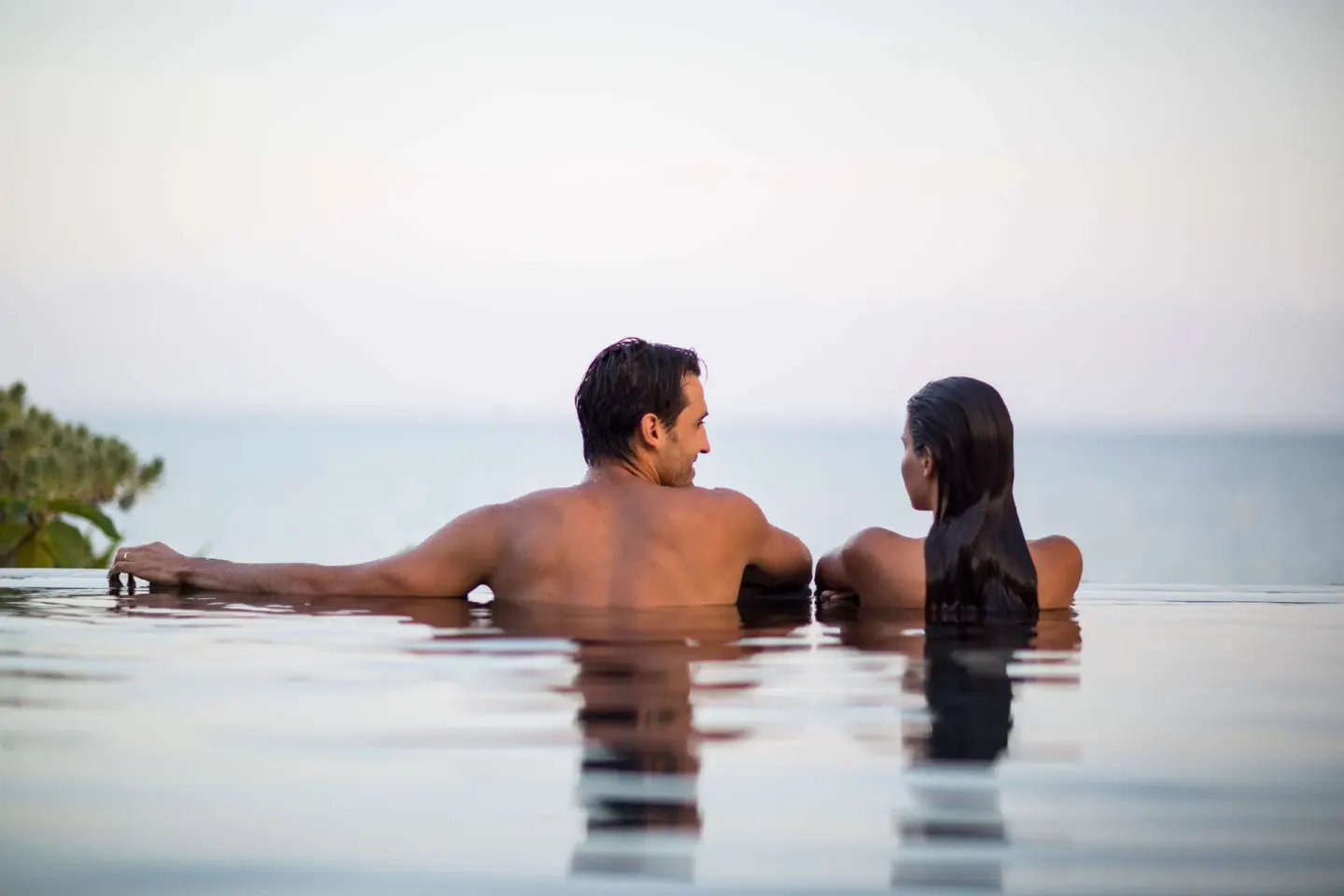 A couple relaxes at the edge of an infinity pool overlooking the sea at Nizuc Resort and Spa.