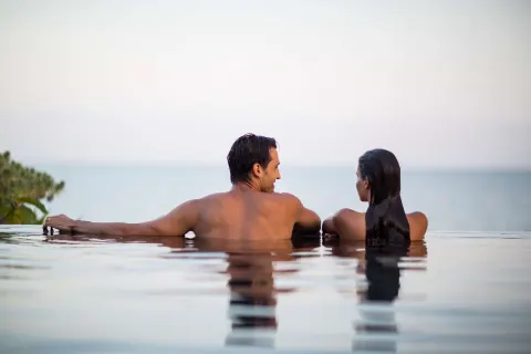 A couple relaxes at the edge of an infinity pool overlooking the sea at Nizuc Resort and Spa.