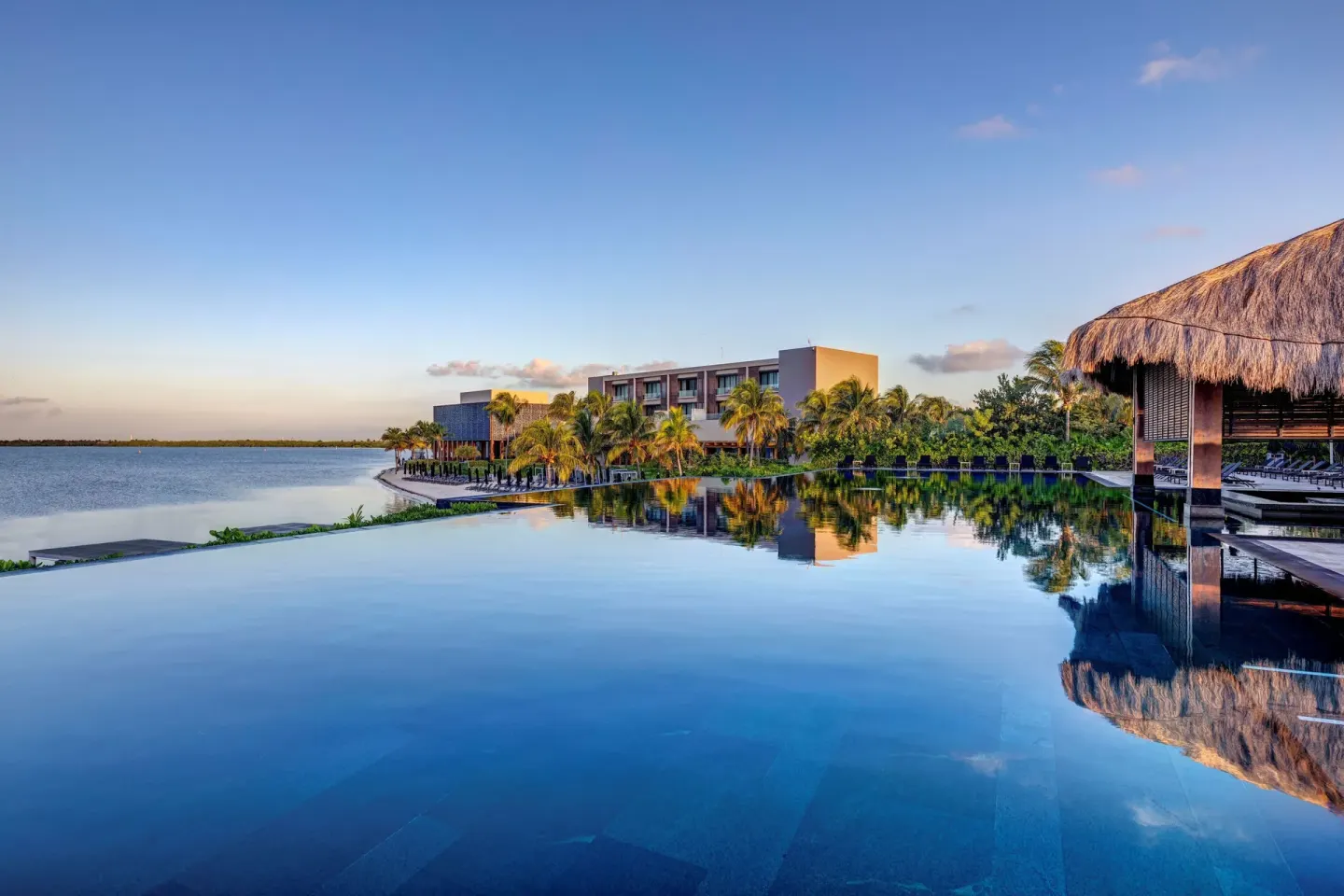 Large infinity pool reflecting palms and resort buildings at Nizuc Resort and Spa.