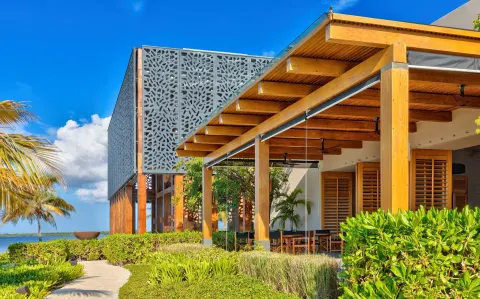 Modern resort exterior with wood beams and tropical landscaping at Nizuc Resort and Spa.