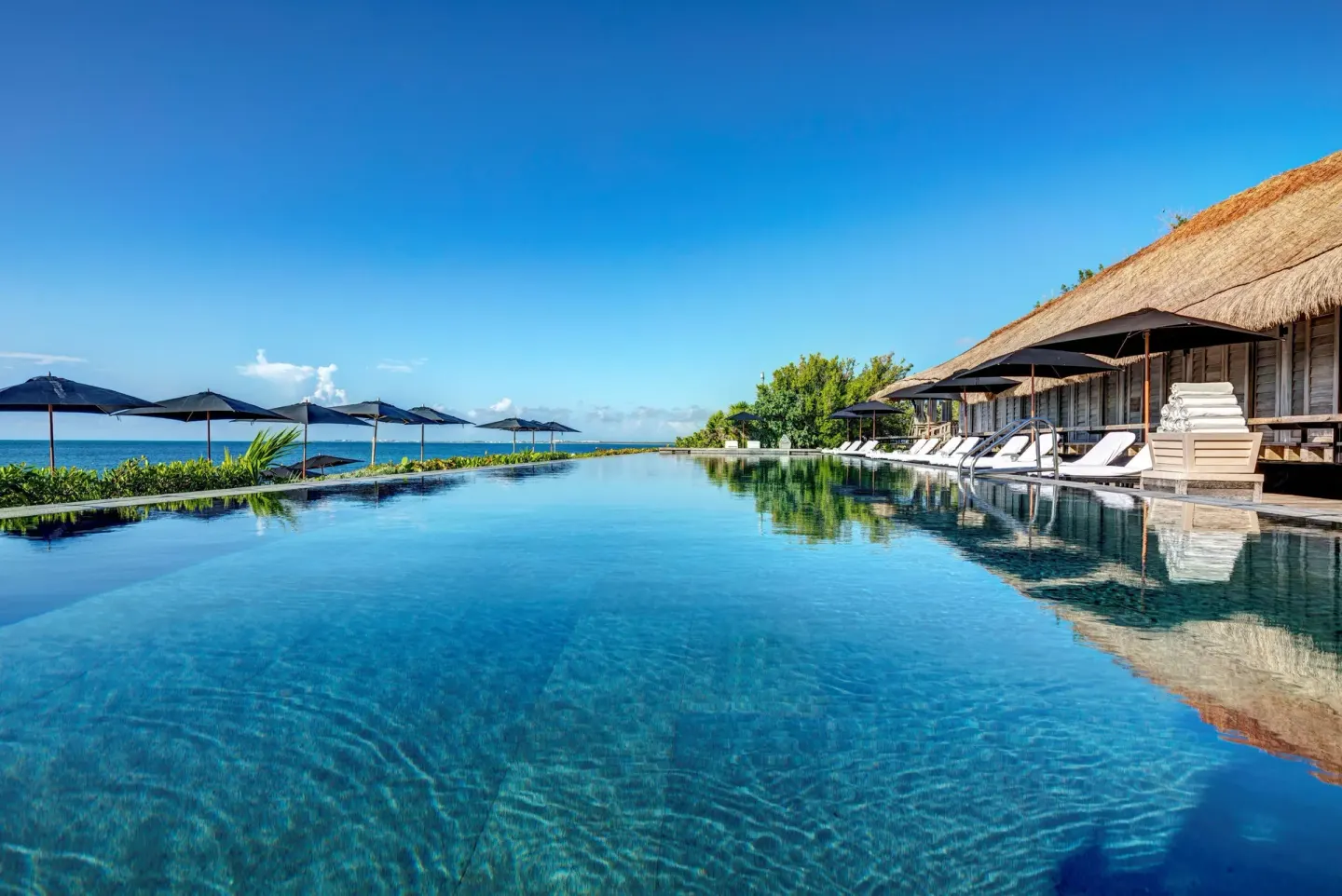 Infinity pool with loungers and ocean view at Nizuc Resort and Spa.
