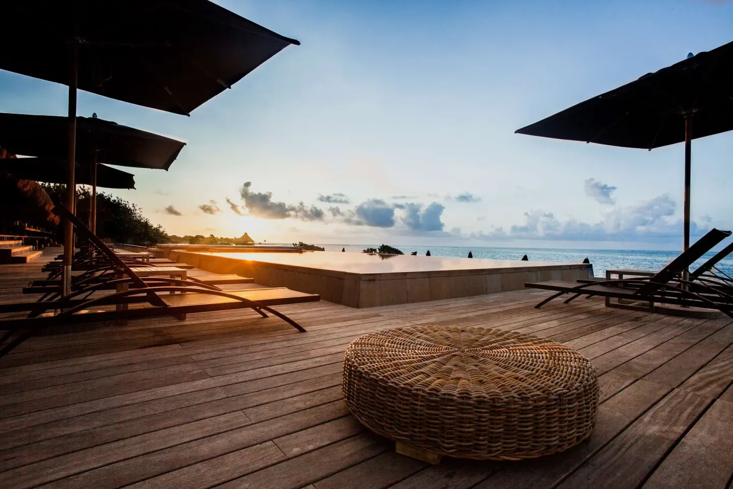 Lounge chairs and umbrellas face the ocean from a wooden deck at Nizuc Resort and Spa.