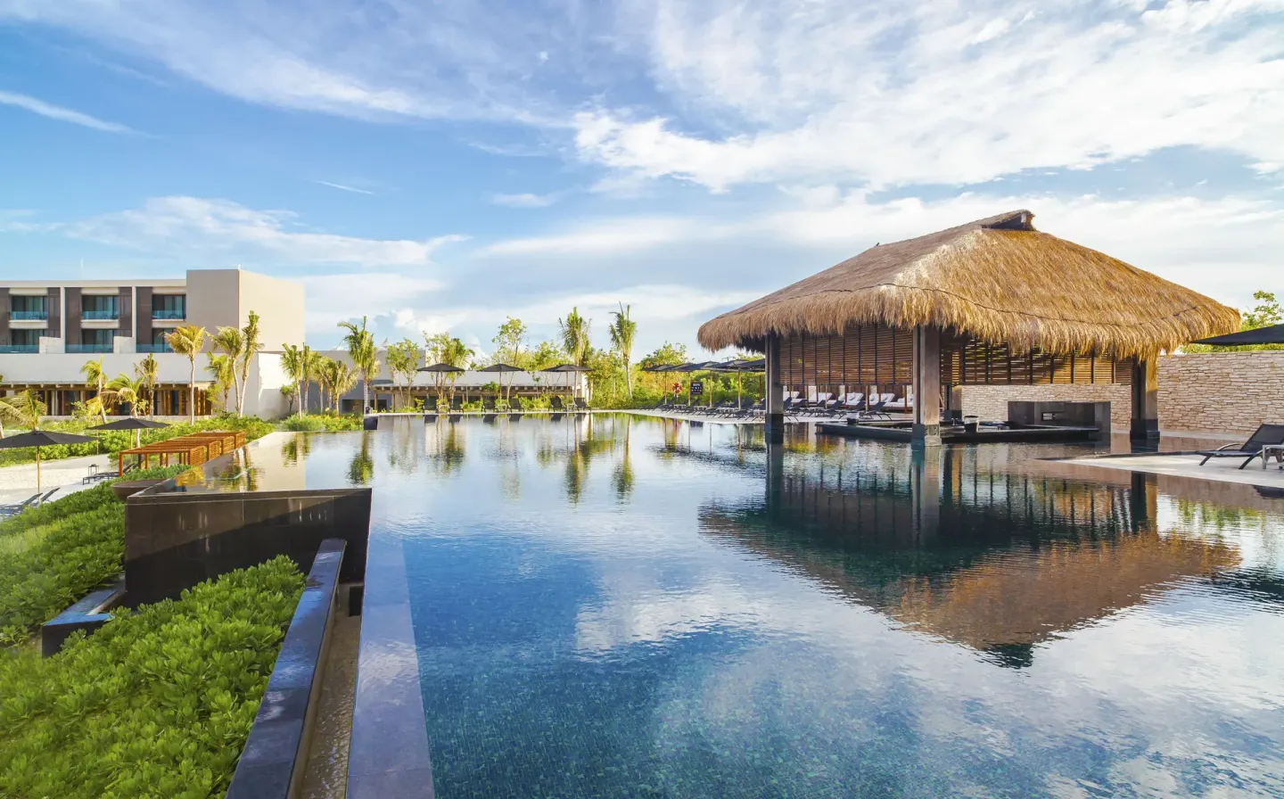 A thatched-roof pavilion stands over a large reflecting pool at Nizuc Resort and Spa.