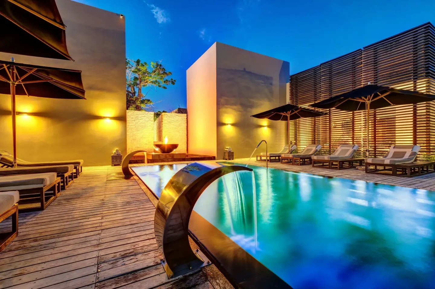 Spa pool with loungers and water features at dusk at Nizuc Resort and Spa.
