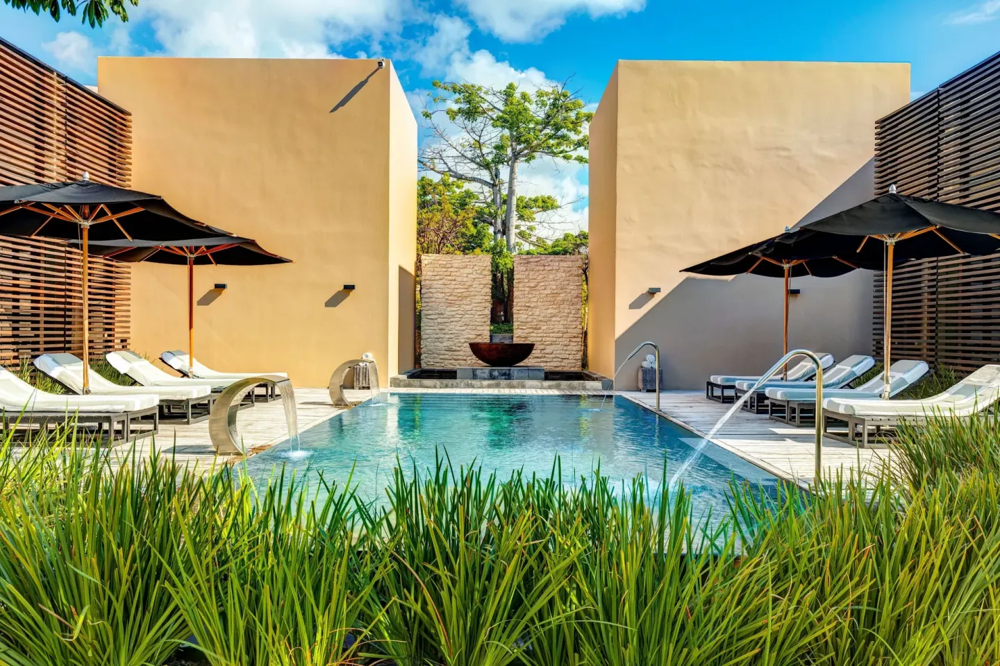 Spa pool courtyard with loungers, umbrellas, and grasses at Nizuc Resort and Spa.