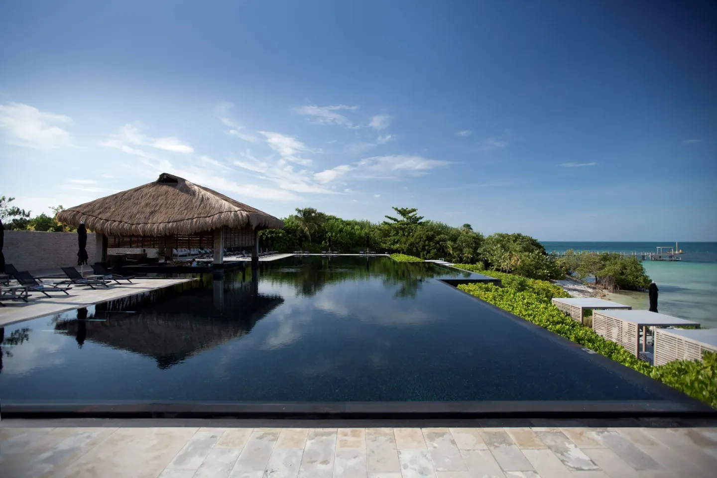 An infinity pool with a thatched pavilion overlooks the turquoise sea at Nizuc Resort and Spa.