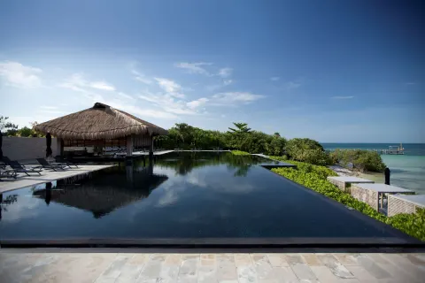 An infinity pool with a thatched pavilion overlooks the turquoise sea at Nizuc Resort and Spa.