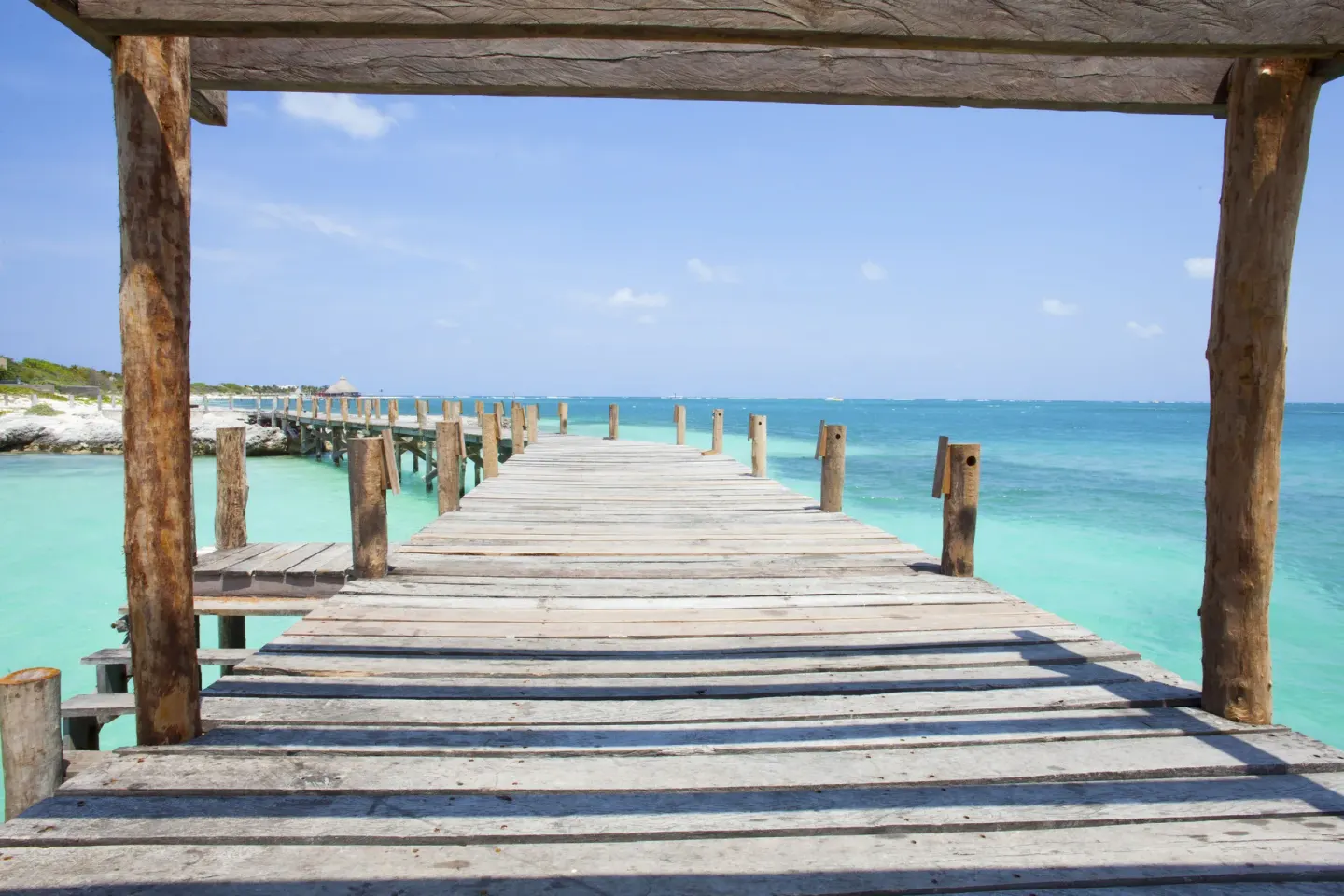 A wooden pier extends over turquoise water at Nizuc Resort and Spa.