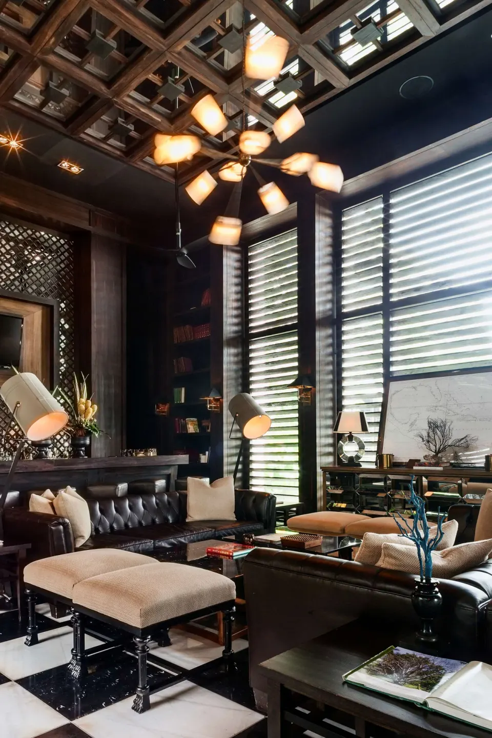 Dark lounge with leather seating, shuttered windows, bookshelves, and chandelier at Nizuc Resort and Spa.