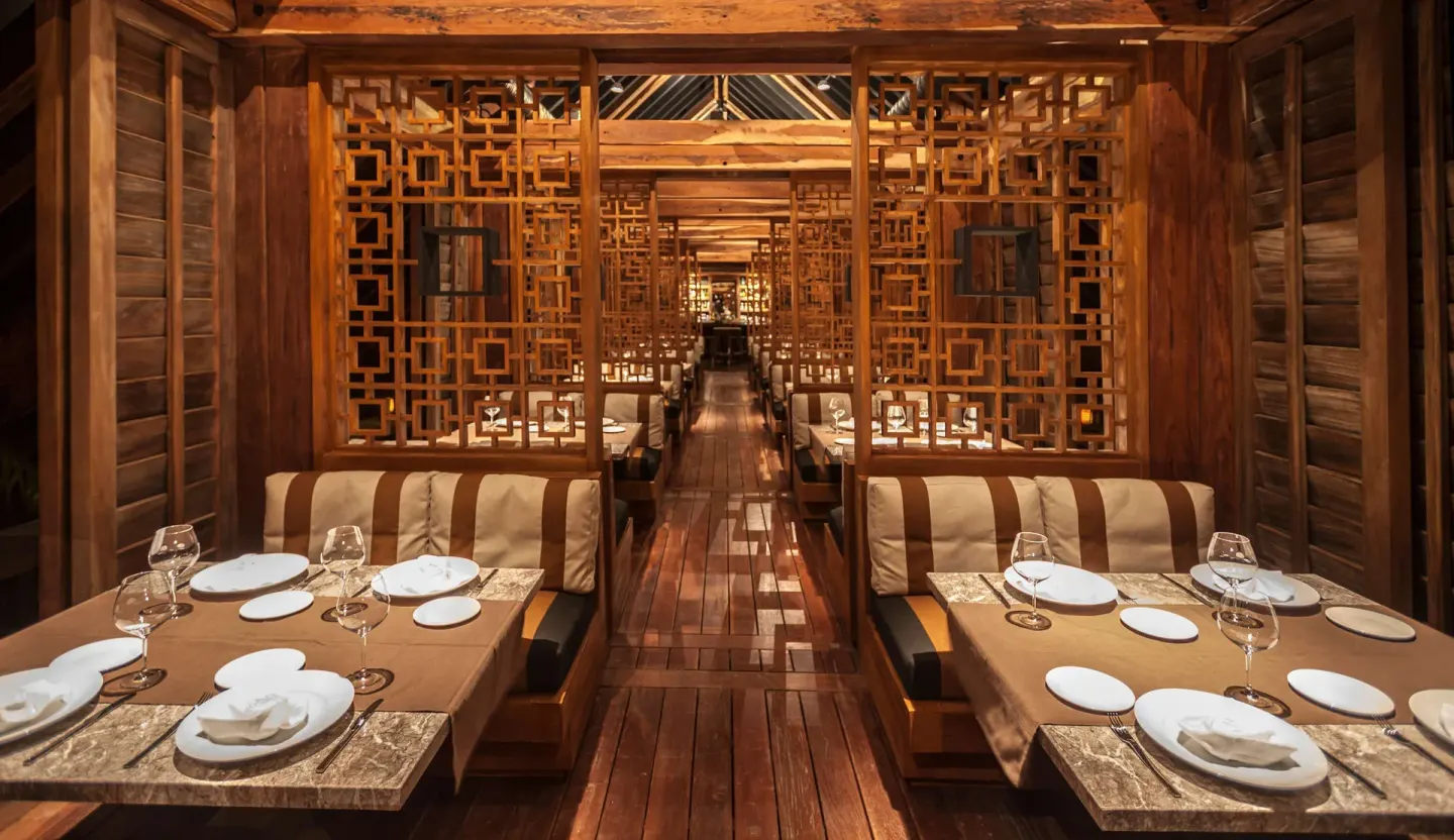 Wooden dining booths with geometric screens in a restaurant at Nizuc Resort and Spa.