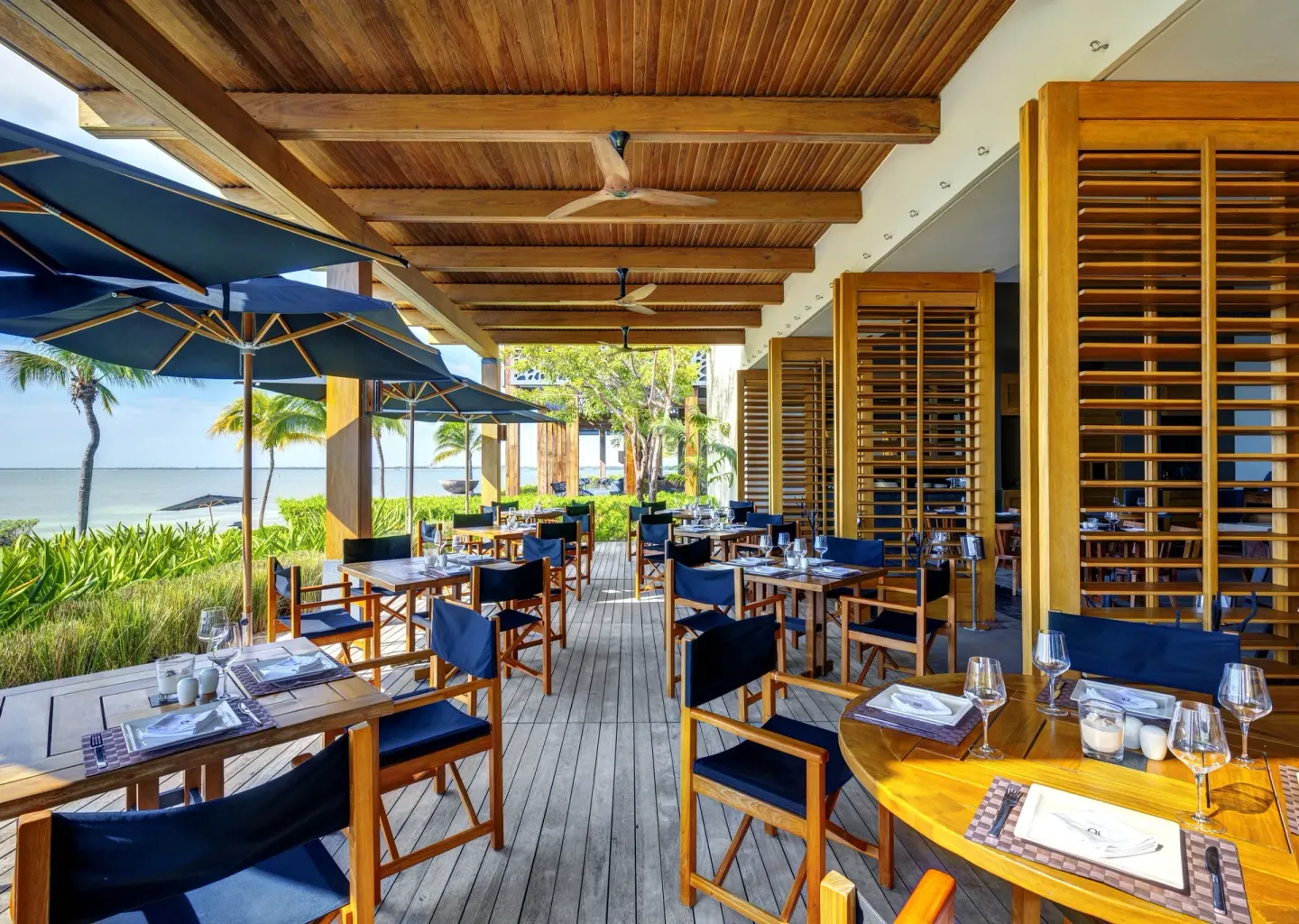 Waterfront terrace dining with blue umbrellas at Nizuc Resort and Spa.