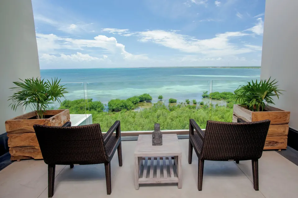 Ocean-view balcony seating for a Deluxe Room at Nizuc Resort and Spa overlooking turquoise water.