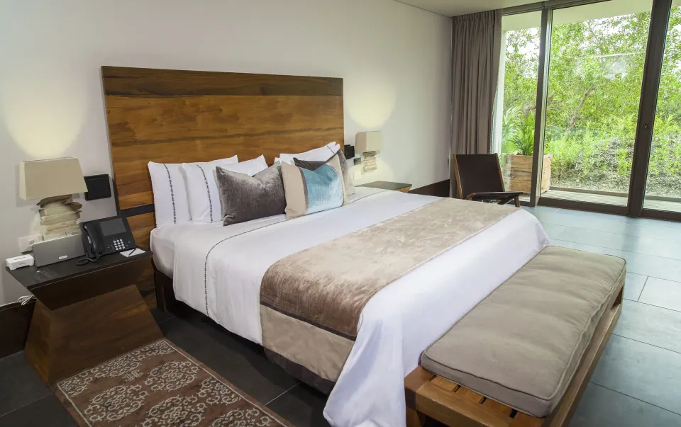 Garden Deluxe Suite bedroom with king bed and greenery view at Nizuc Resort and Spa.