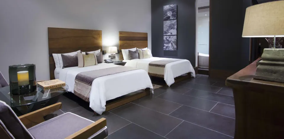 A Garden View room with two beds, armchair, table, and console at Nizuc Resort and Spa.