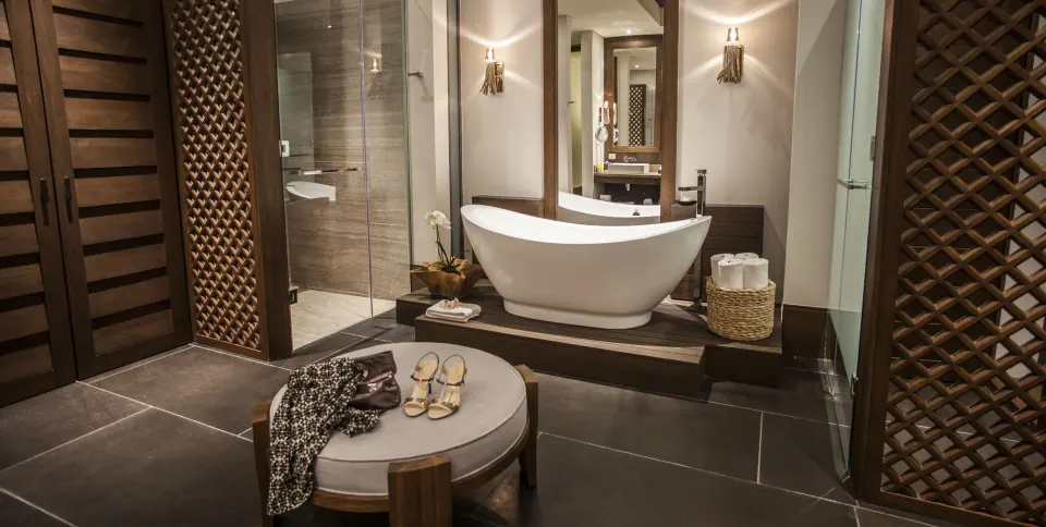 Junior Suite garden bathroom with soaking tub, shower, and dressing bench at Nizuc Resort and Spa.