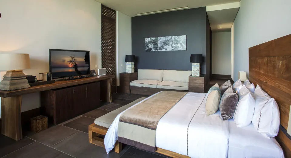 Penthouse king bedroom with sofa, TV and wood furnishings at Nizuc Resort and Spa.