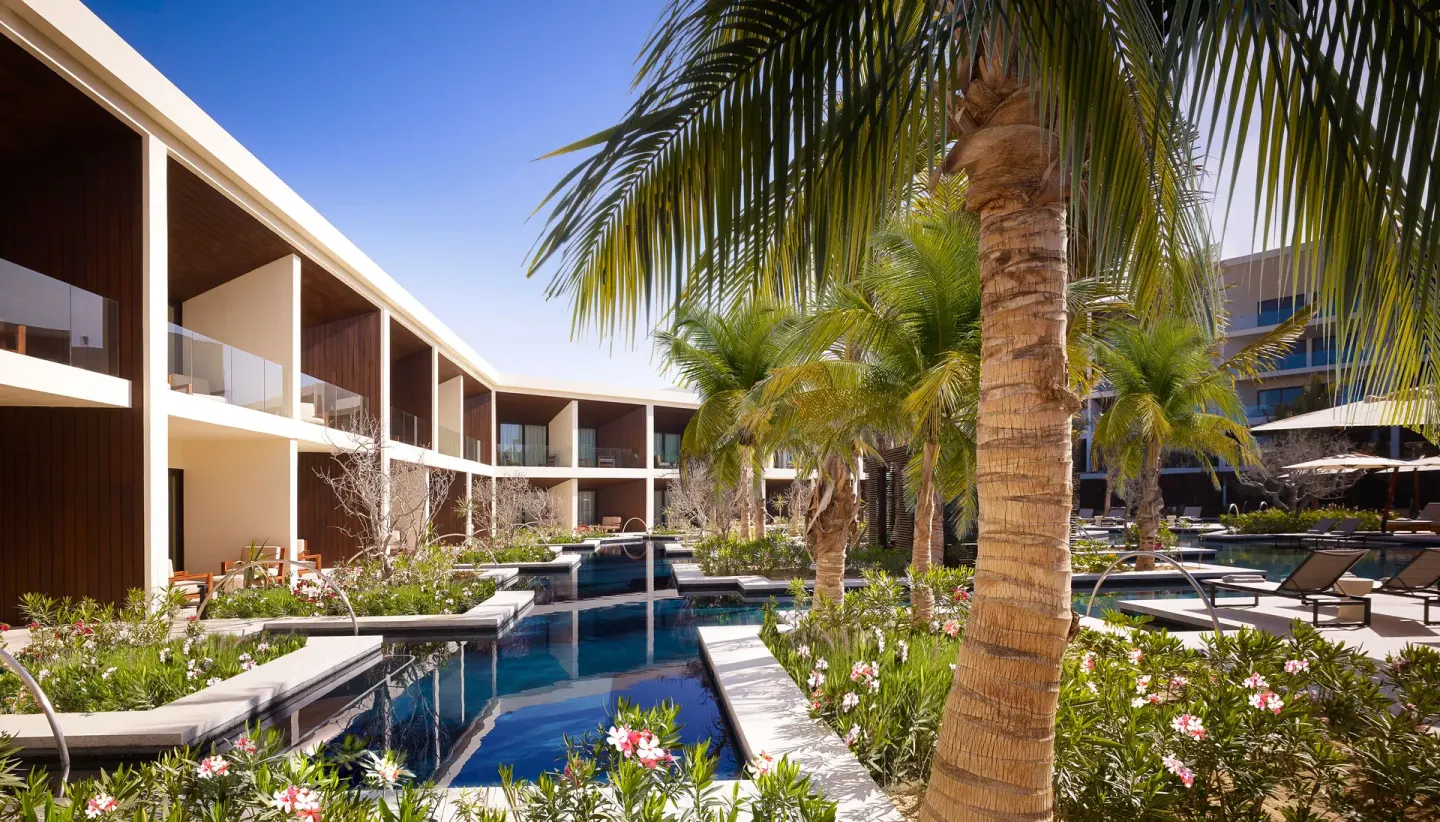 Garden water channels with palms and guest room balconies at Nobu Hotel Los Cabos.