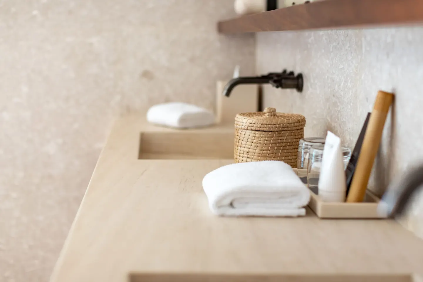 Bathroom counter with folded towels, basket and amenities at Nobu Hotel Los Cabos.