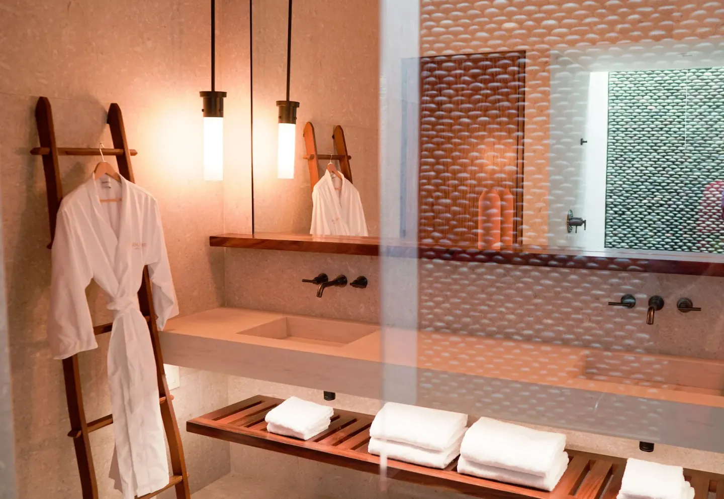 Bathroom vanity with robe, mirror and folded towels at Nobu Hotel Los Cabos.