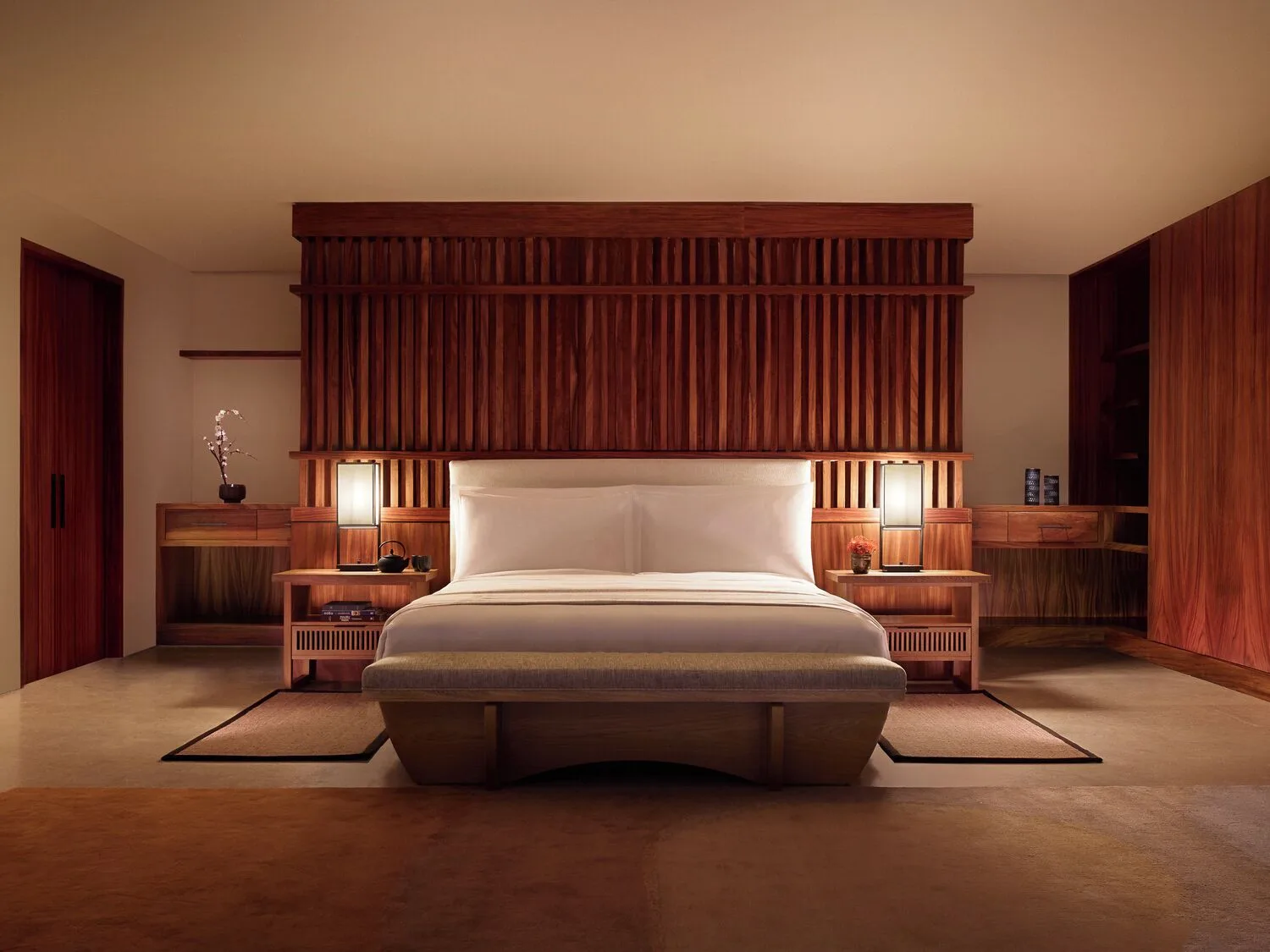 Warmly lit guest room with king bed and wood slat headboard at Nobu Hotel Los Cabos.