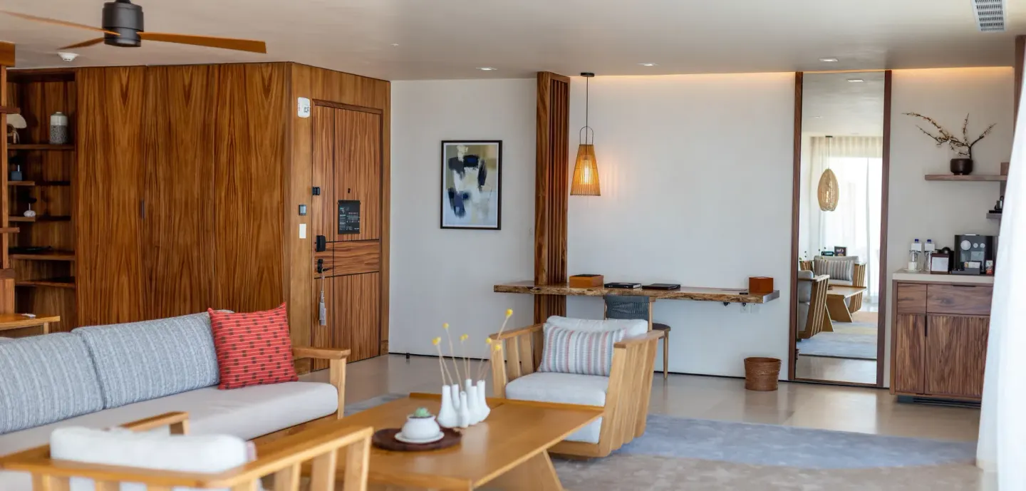 Guest room sitting area with sofa, lounge chair and refreshment cabinet at Nobu Hotel Los Cabos.