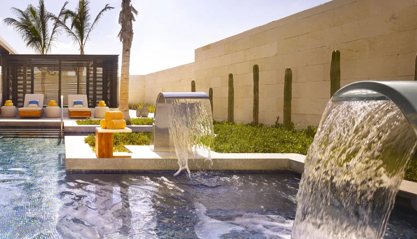Spa pool waterfall features with loungers and cacti at Nobu Hotel Los Cabos.