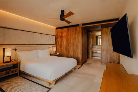 King bedroom with TV and bathroom entry in an Asahi residence at Nobu Hotel Los Cabos.
