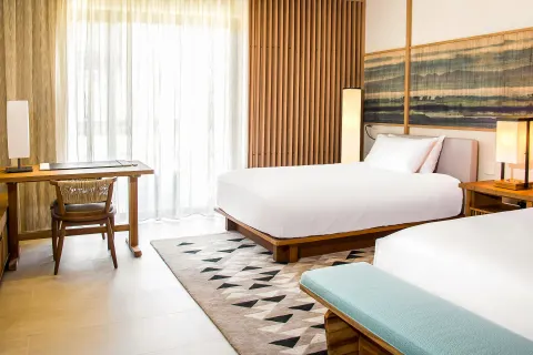 Deluxe Room double beds with writing desk and sheer curtains at Nobu Hotel Los Cabos.