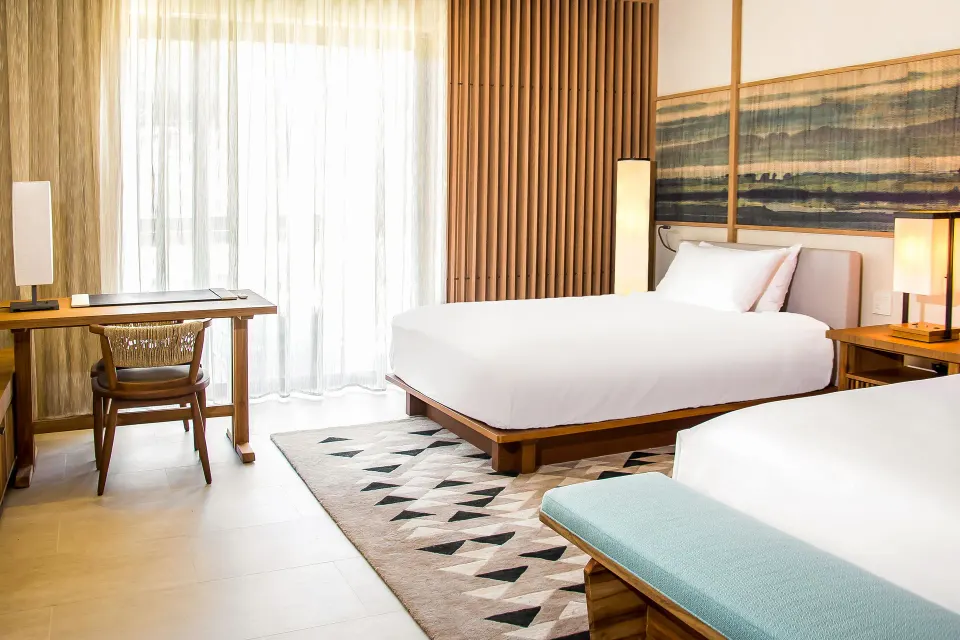 Deluxe Room double beds with writing desk and sheer curtains at Nobu Hotel Los Cabos.