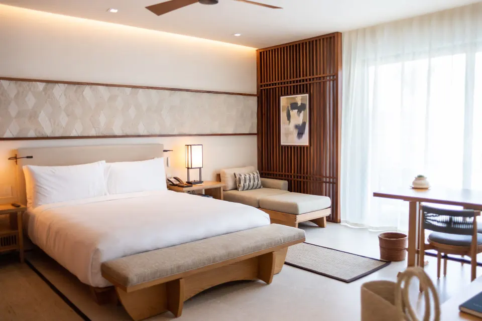Deluxe Room king bed with chaise, desk, and sheer window curtains at Nobu Hotel Los Cabos.