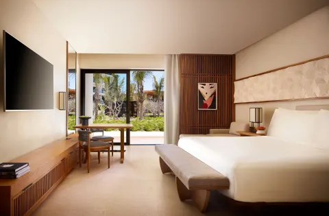 Deluxe Room with king bed, TV and garden-facing glass doors at Nobu Hotel Los Cabos.