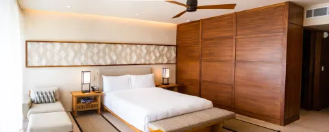 Deluxe Room king bed with wood wardrobe wall and chaise at Nobu Hotel Los Cabos.