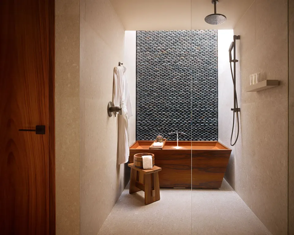 Deluxe Room shower and wooden soaking tub behind glass at Nobu Hotel Los Cabos.