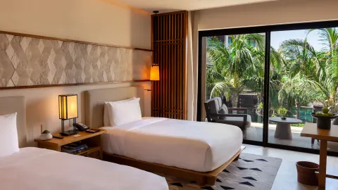 Deluxe Room with two beds, balcony, and palms at Nobu Hotel Los Cabos.