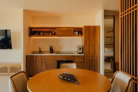 Hikari One Bedroom at Nobu Hotel Los Cabos with dining table, kitchenette and bedroom doorway.
