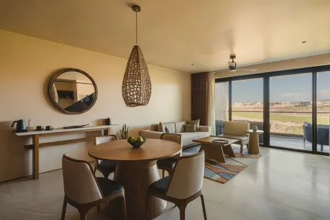 Hikari One Bedroom at Nobu Hotel Los Cabos with dining table, sofa and balcony doors.