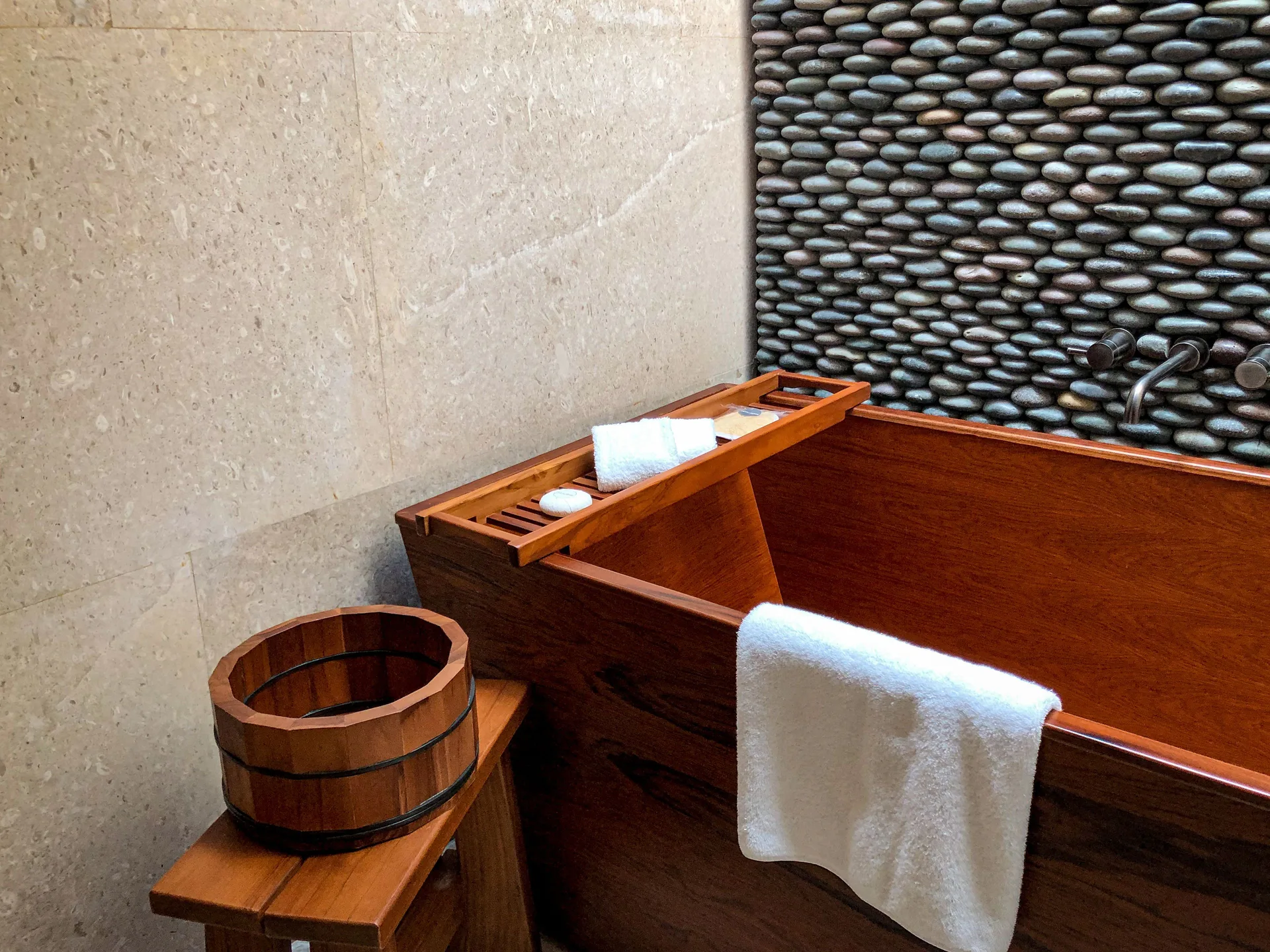 Hikari One Bedroom at Nobu Hotel Los Cabos bathroom with wooden soaking tub and pebble wall.