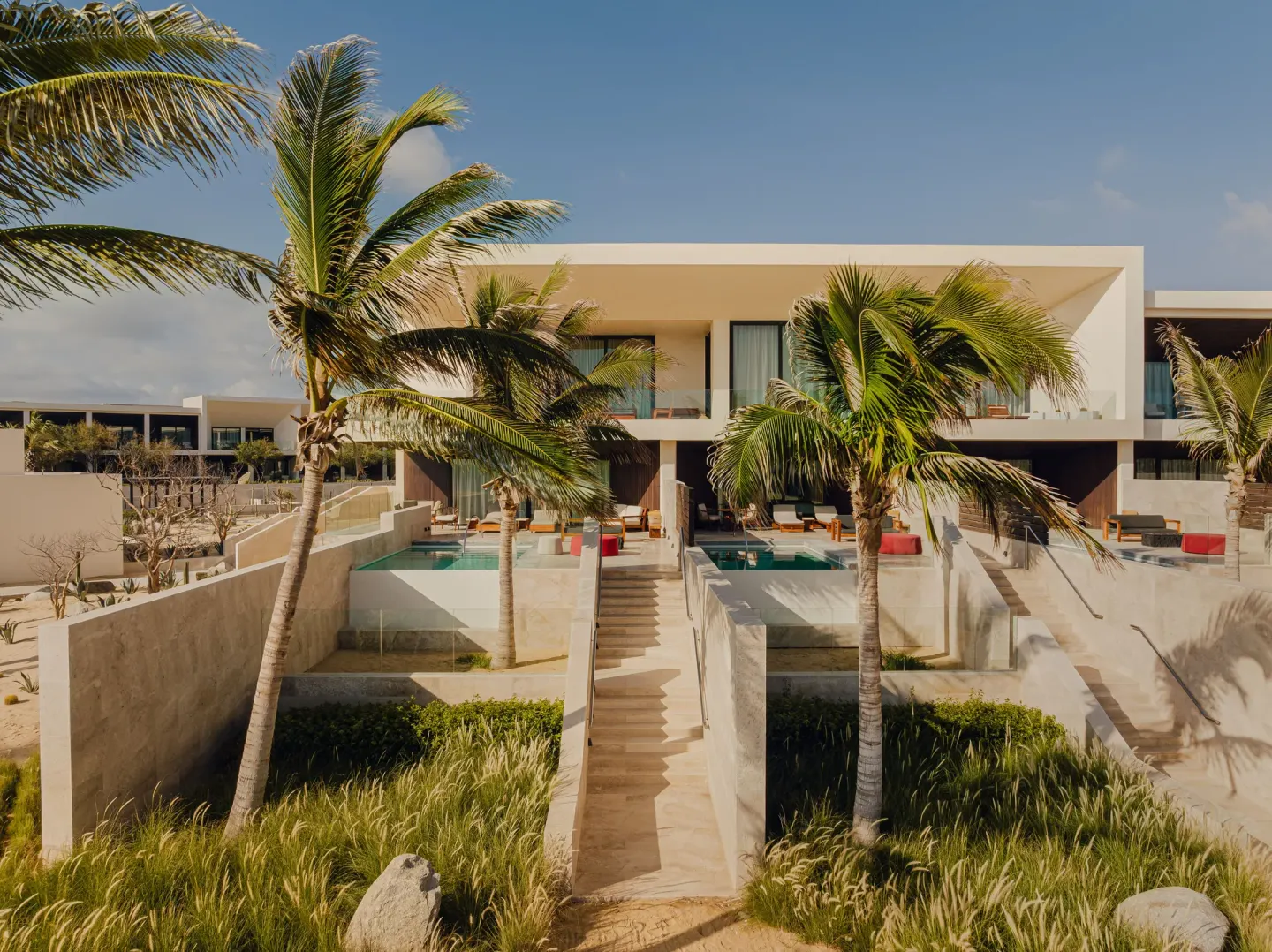 Oceanfront junior room buildings at Nobu Hotel Los Cabos with private pools and palm-lined paths.