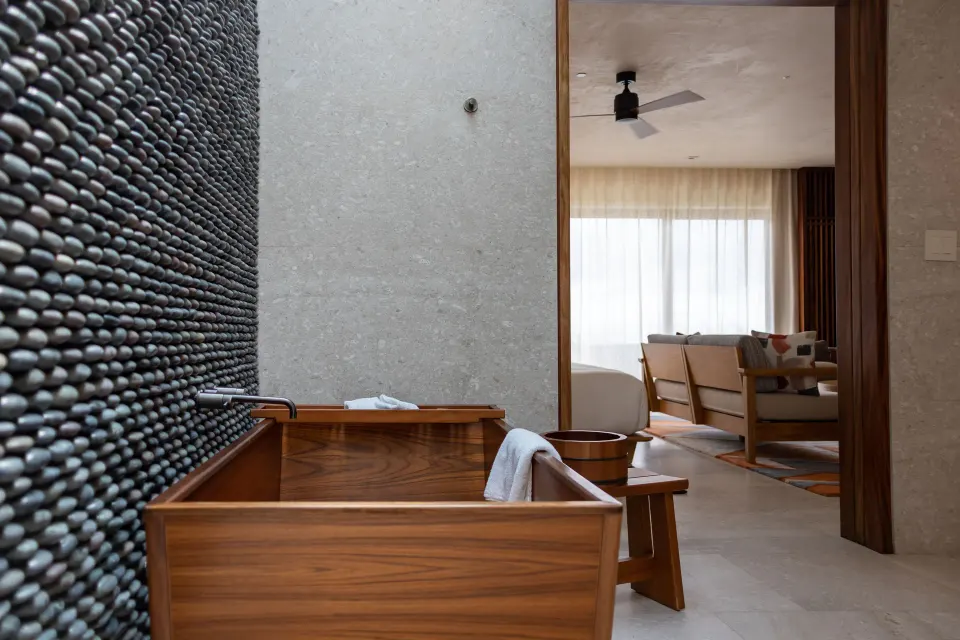 Wooden soaking tub in an oceanfront junior room at Nobu Hotel Los Cabos, with the living area beyond.