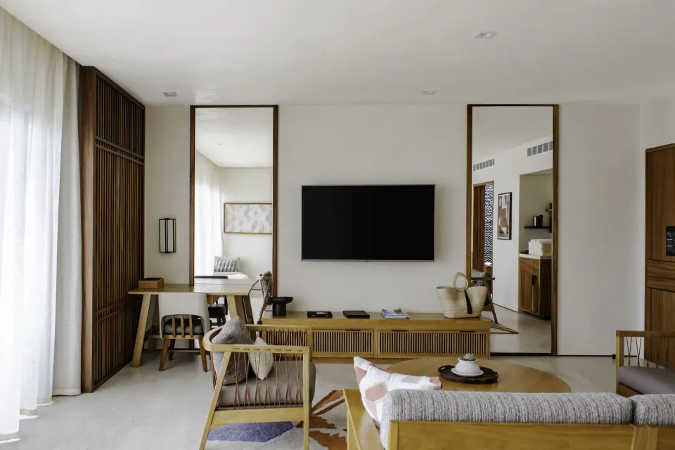 Junior Room living area with TV, desk, mirrors, and sofa at Nobu Hotel Los Cabos.
