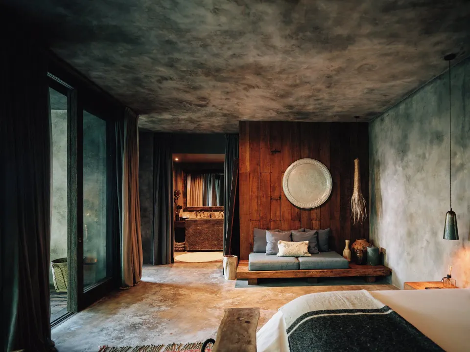 Bedroom with a low daybed and textured wall art at Nômade Temple Tulum