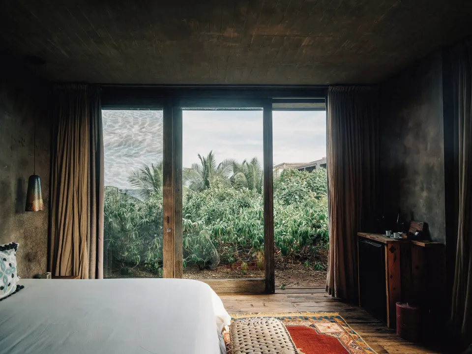Bedroom with king bed and sliding glass doors to garden at Nômade Temple Tulum