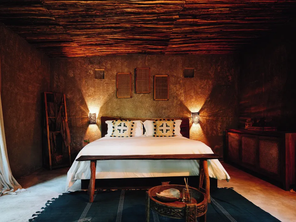Bedroom with king bed and rustic ceiling lighting at Nômade Temple Tulum