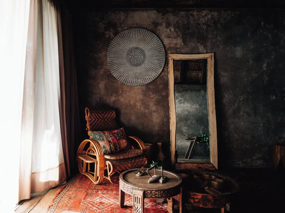 Cozy seating nook with rattan chair and full-length mirror at Nômade Temple Tulum