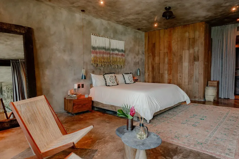 Spacious king bed guest room with natural wood accents at Nômade Temple Tulum